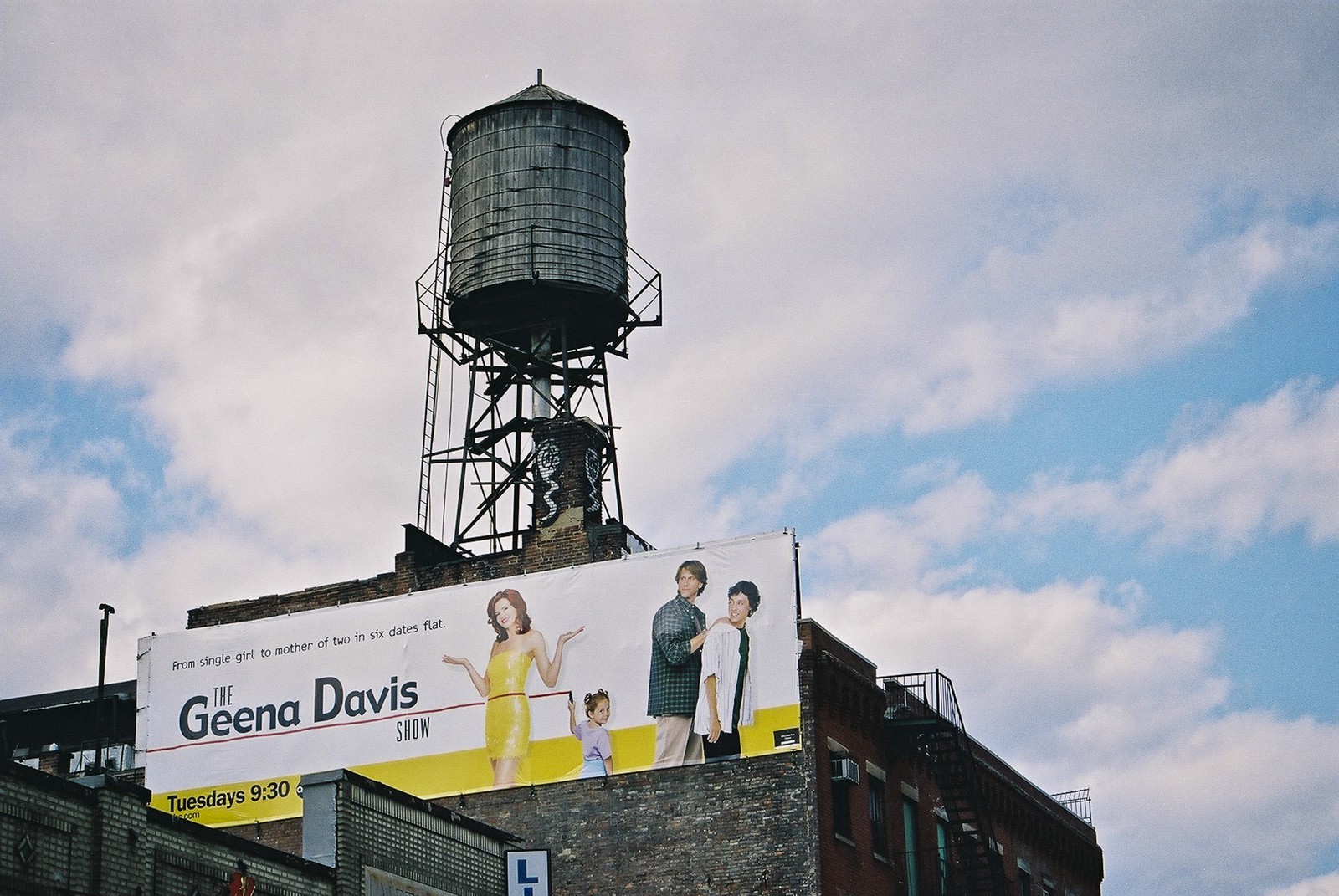 Citerne d'eau sur le toit d'un immeuble au dessus d'une publicité murale sur un immeuble de Chinatown. - Water tank on the roof of a building on top of an advertising mural on a building in Chinatown.